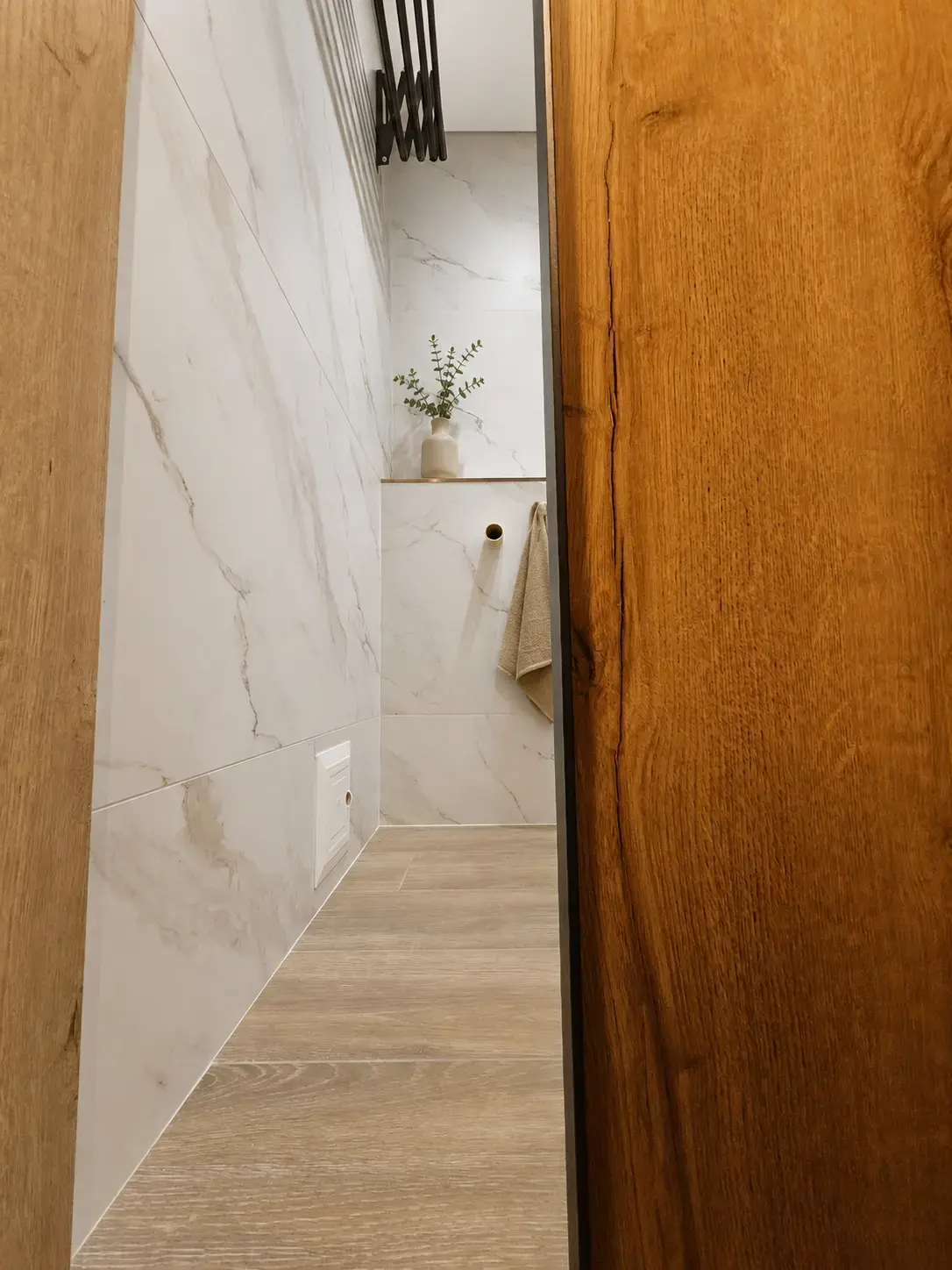 Pasillo con porcelanato tipo mármol y puerta de madera