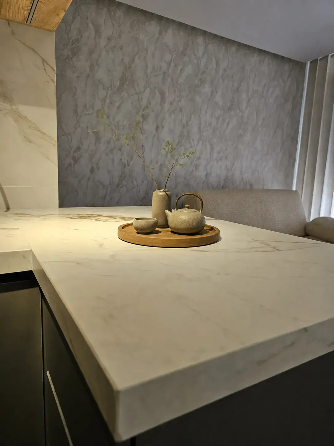 Mesón de porcelanato con bandeja de té y pared de piedra
