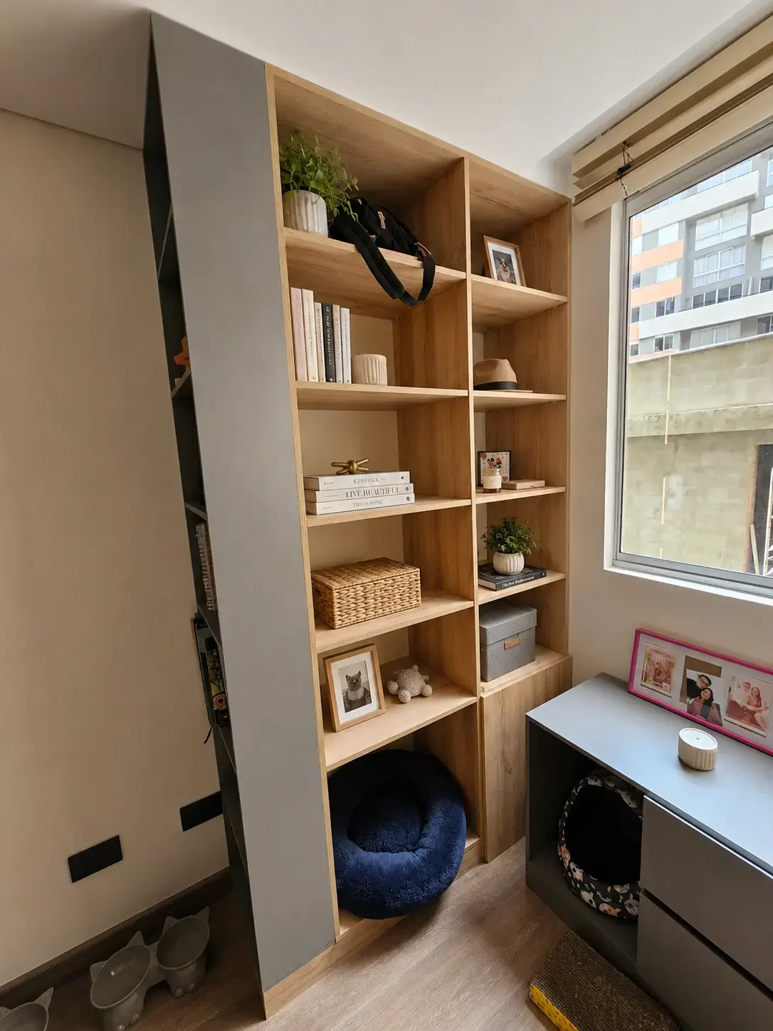 Repisas de madera con mueble gris y ventana en un estudio