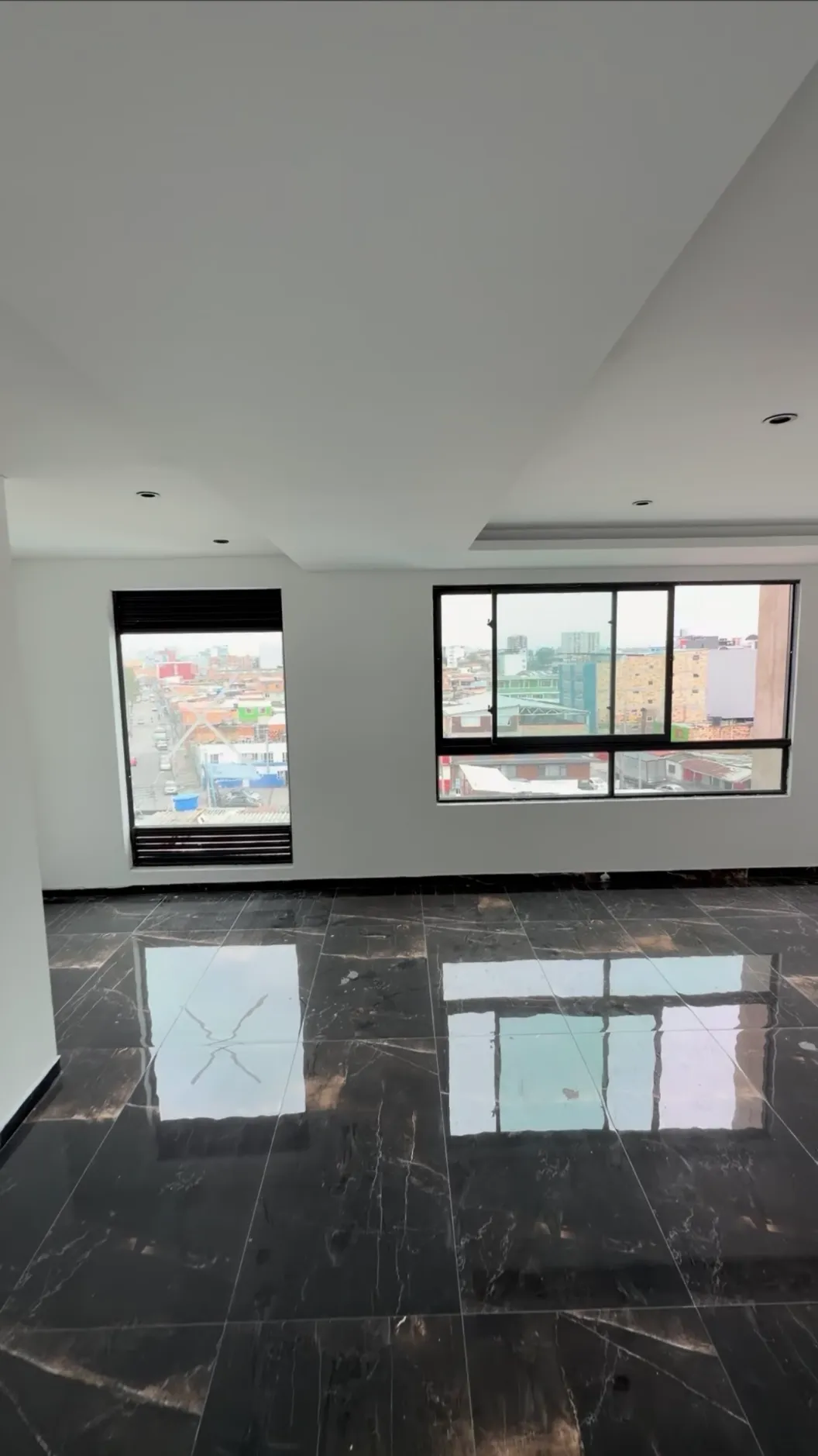Sala sin amoblar con piso de mármol oscuro y ventanas
