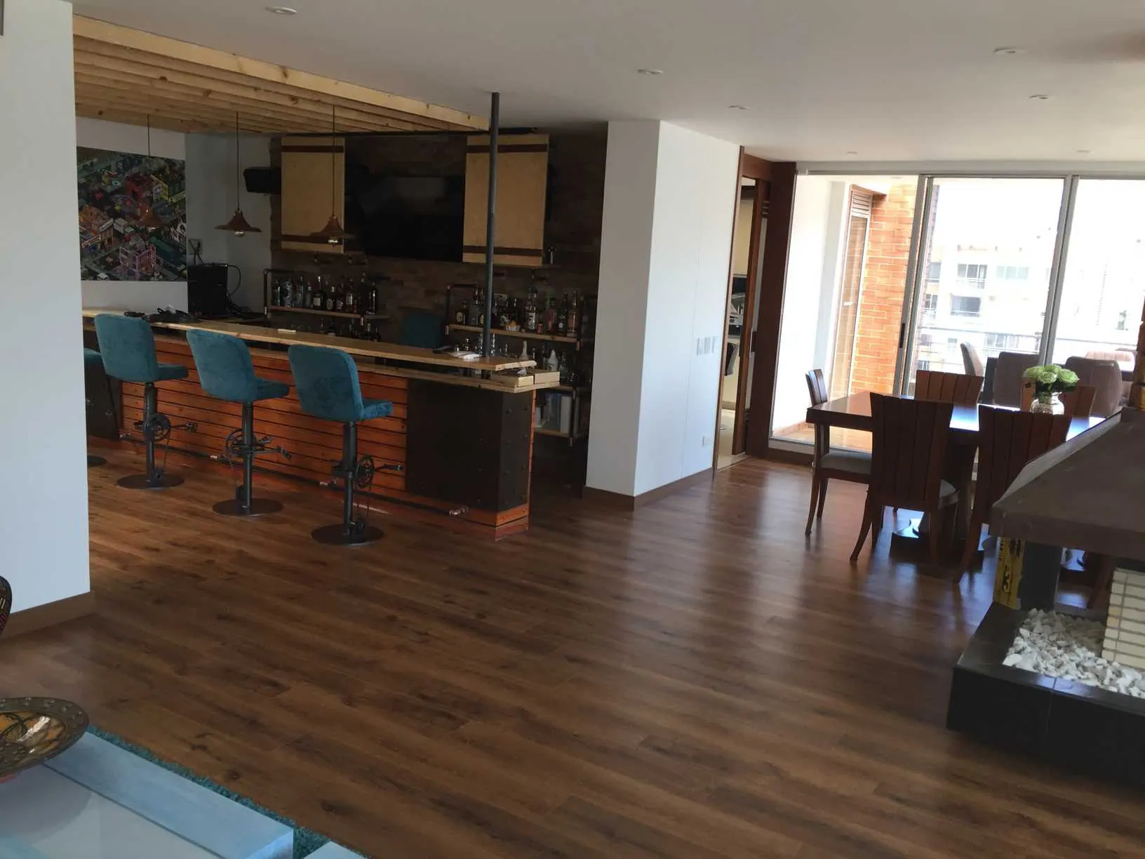 Sala y bar con barra, taburetes azules y piso de madera