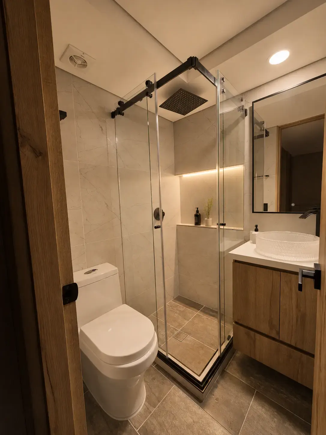Baño con ducha de vidrio de esquina, nicho iluminado y mueble de madera
