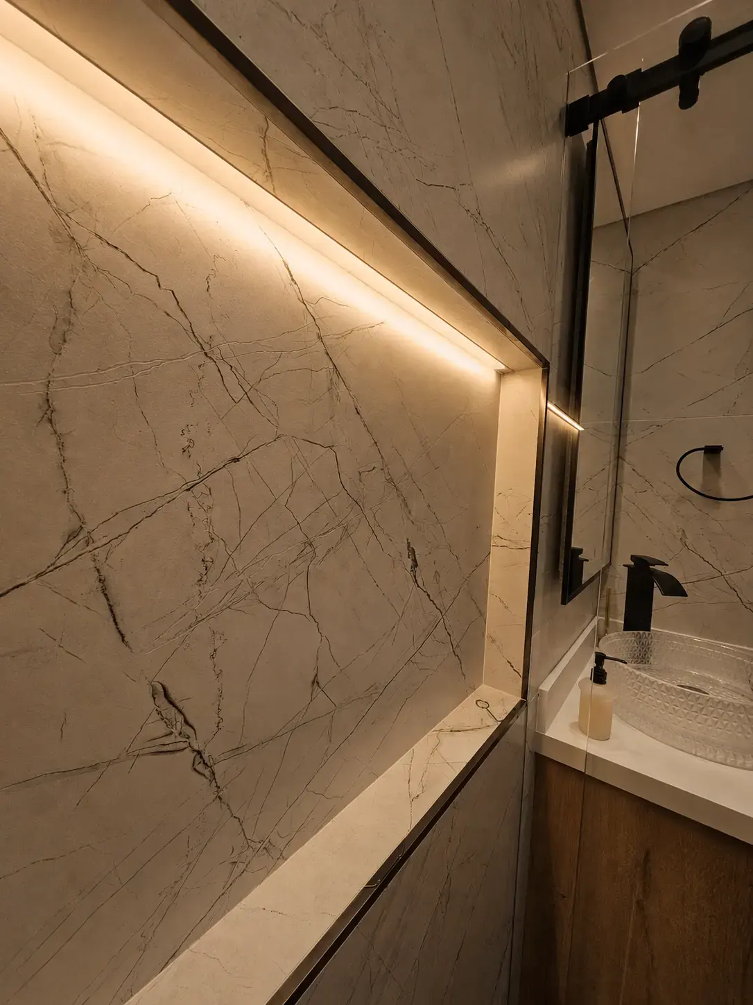 Pared enchapada con nicho de luz LED y lavamanos con mueble de madera