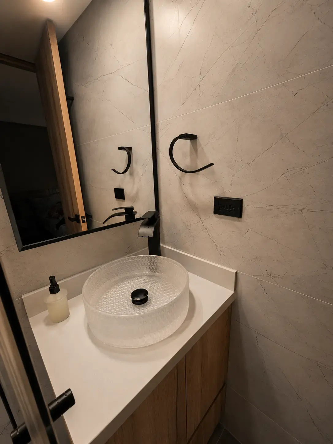 Lavamanos sobre mesón blanco con espejo y mueble de madera