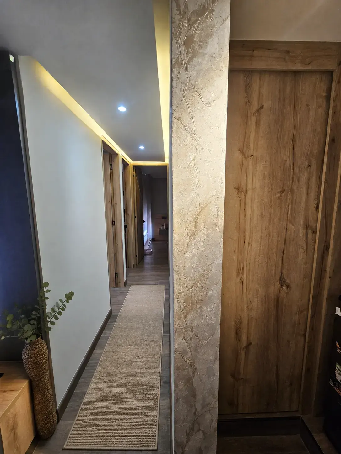 Pasillo con luz LED en el techo, alfombra y puertas de madera