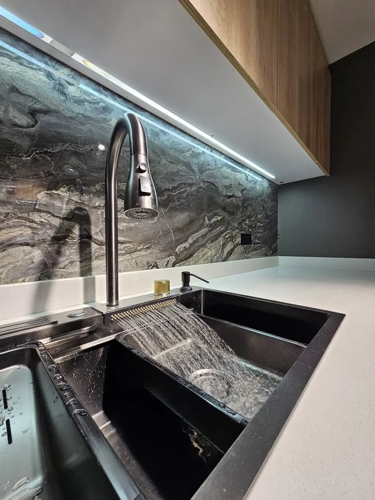 Lavaplatos negro con grifo extraíble, salpicadero de piedra oscura y luz LED