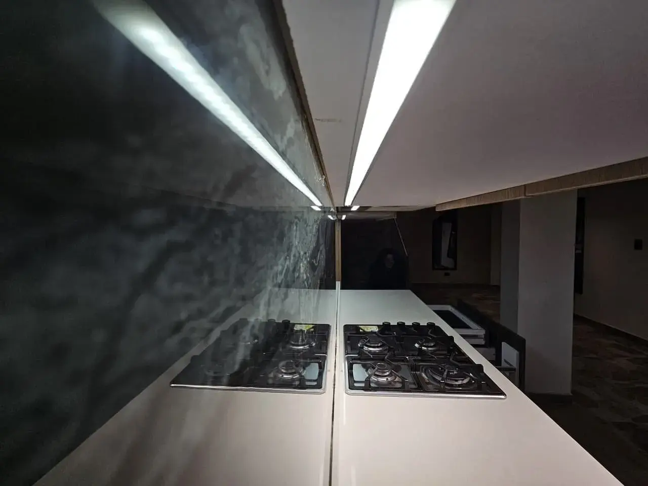 Estufa de gas y salpicadero de piedra oscura con luz LED en la cocina