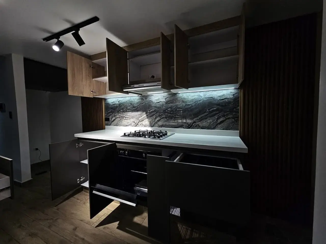 Cocina con gabinetes abiertos, cajones y salpicadero de piedra oscura