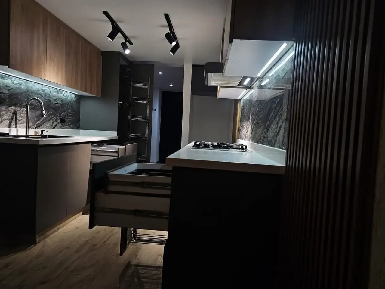 Cocina con estufa de gas, mesón blanco y muebles de madera