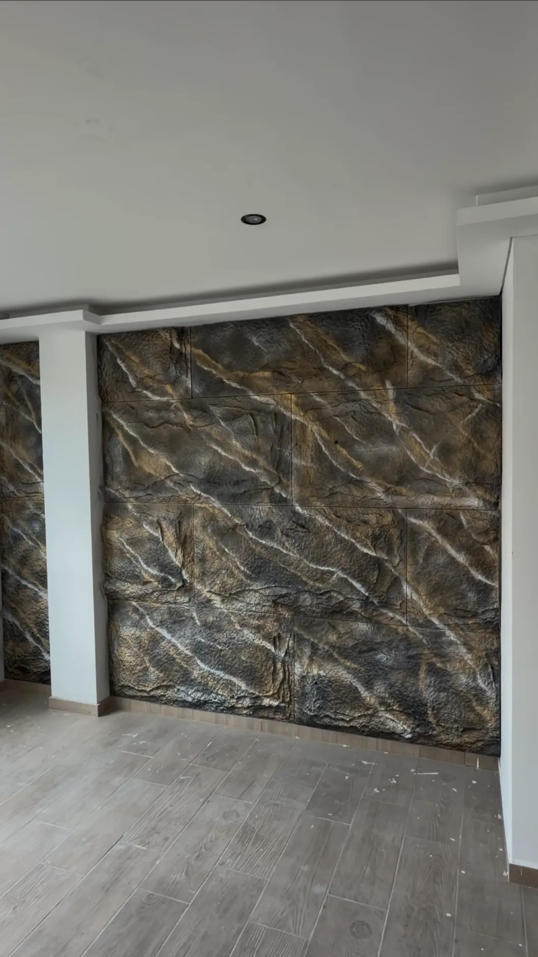Muro con revestimiento de piedra veteada oscura y piso gris