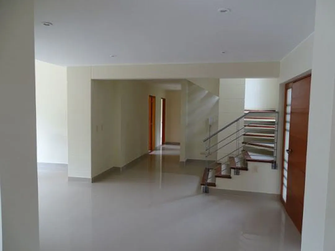 Salón amplio con piso brillante y escalera