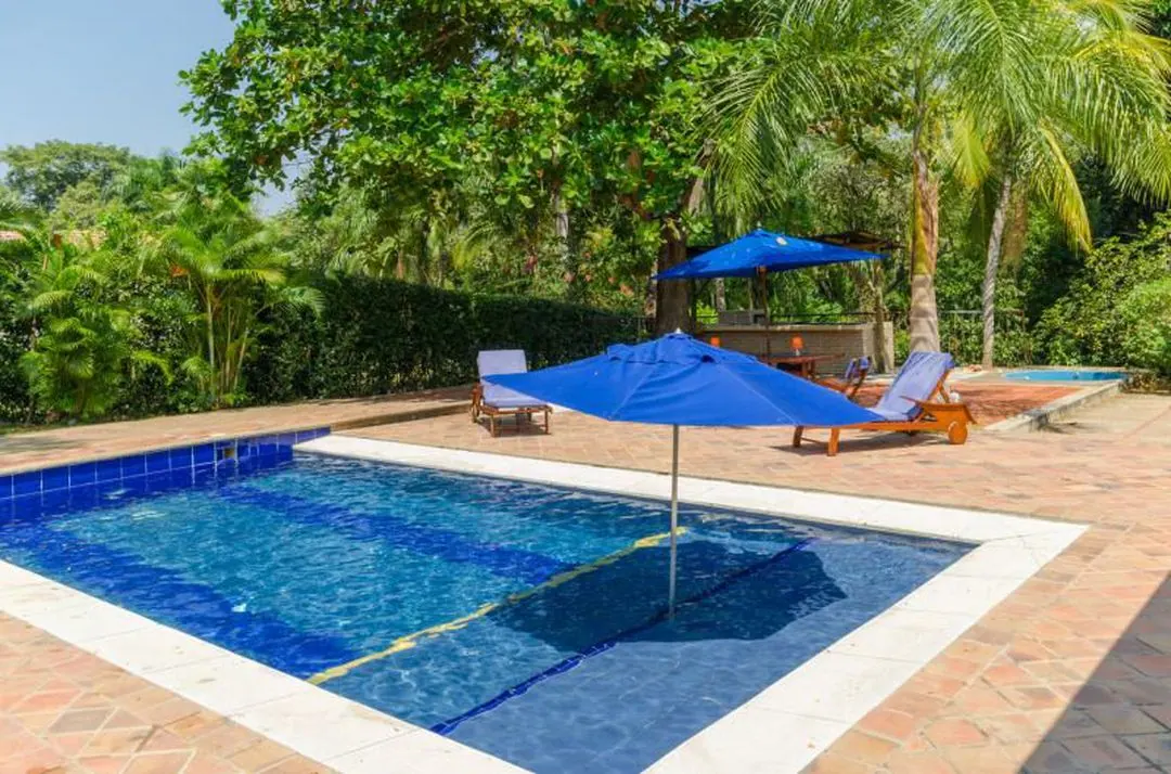 Piscina con sombrillas azules y zona de descanso