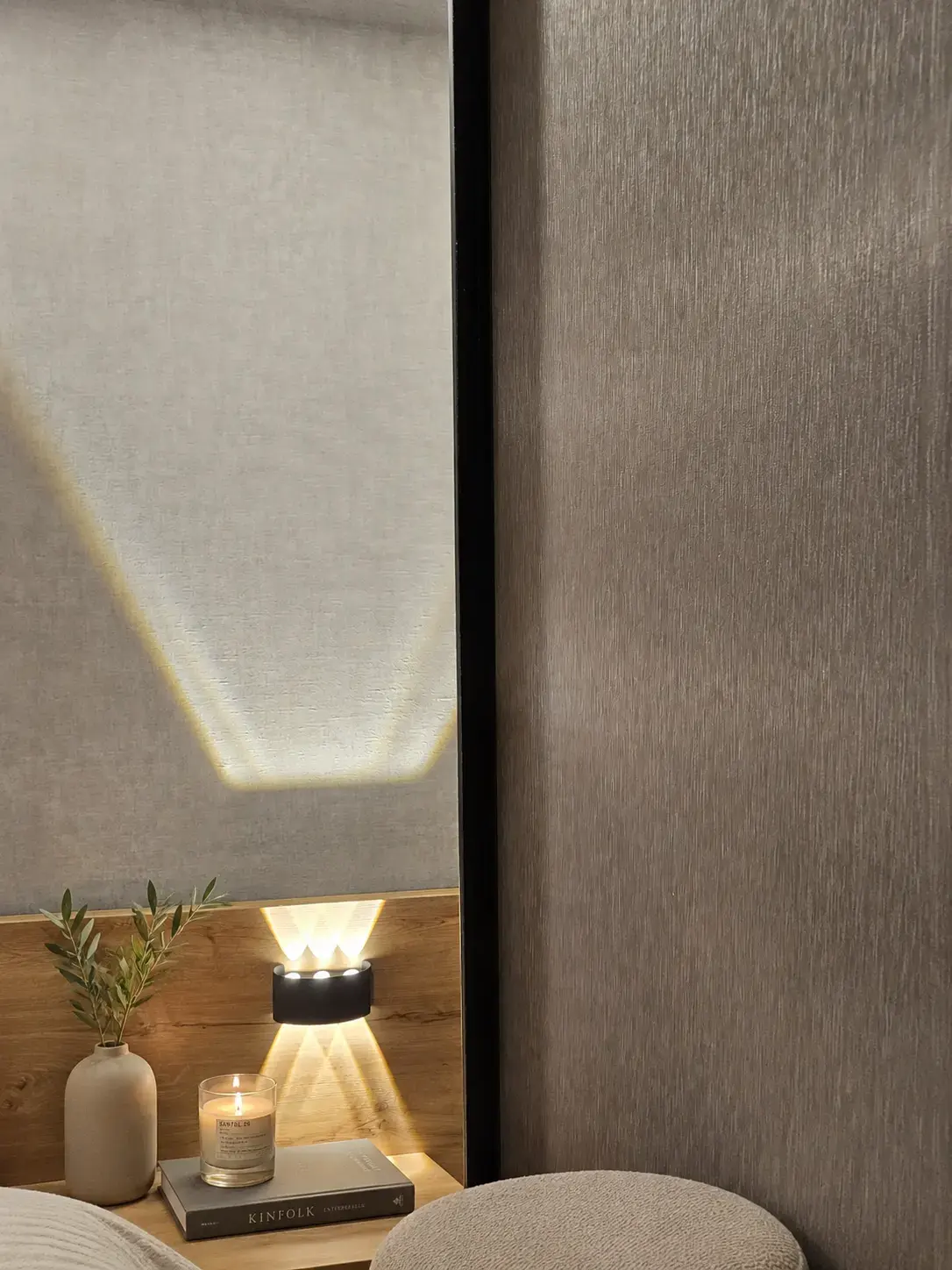 Aplique de luz y pared texturizada junto a la cama