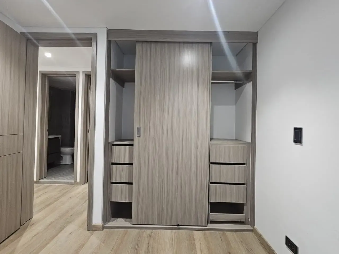 Closet corredizo con cajones y vista al baño en una habitación