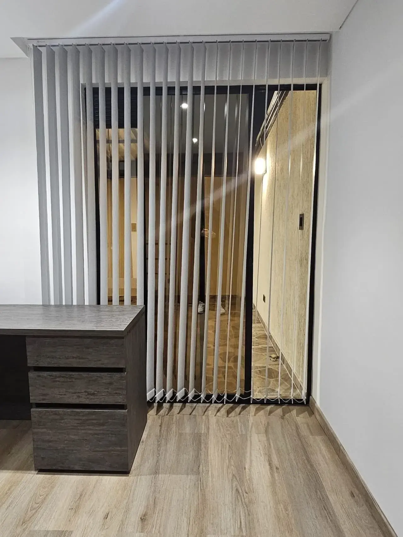 Escritorio con cajones y cortinas verticales en una habitación