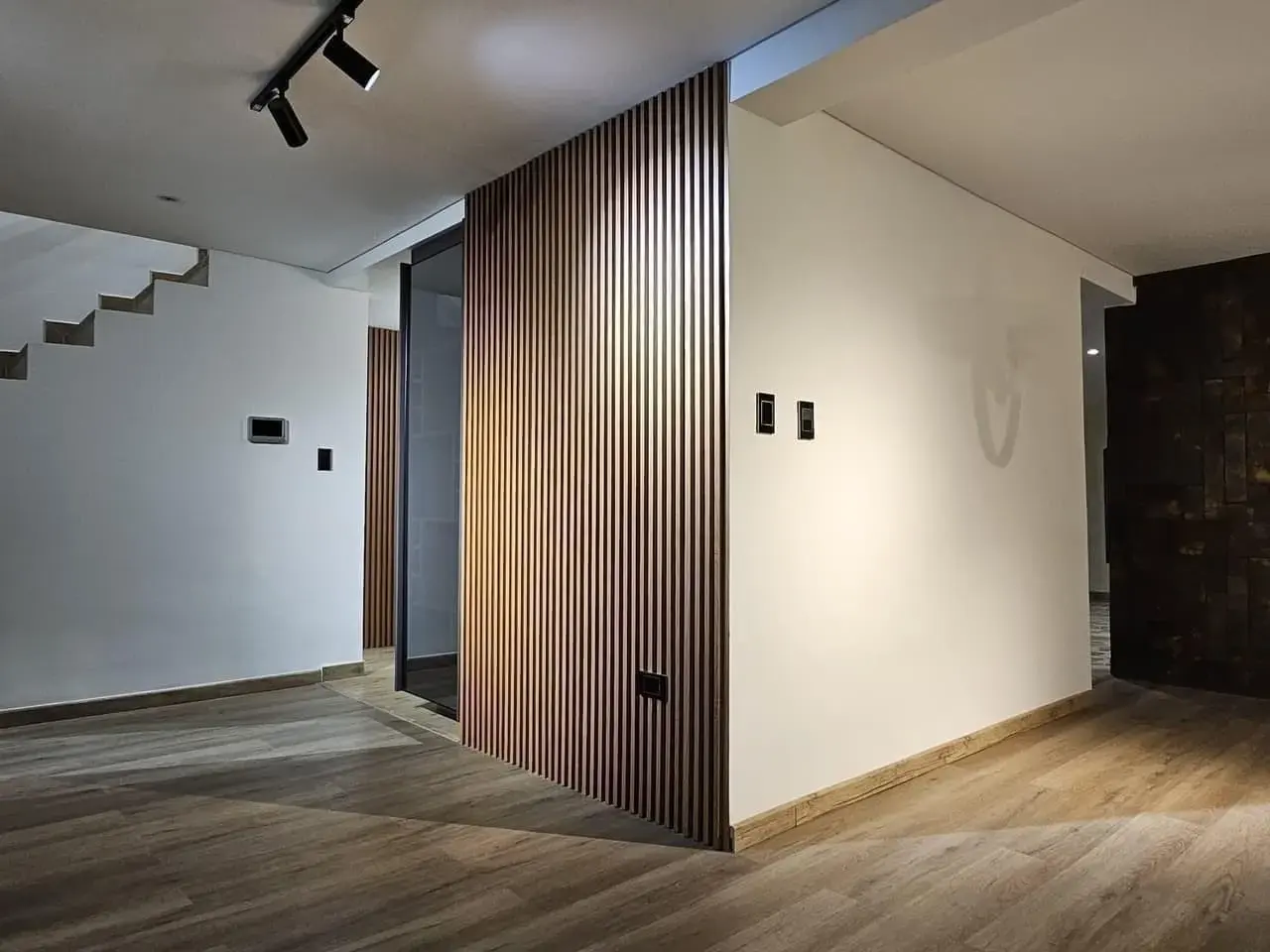 Habitación con divisor de listones de madera y escalera al fondo