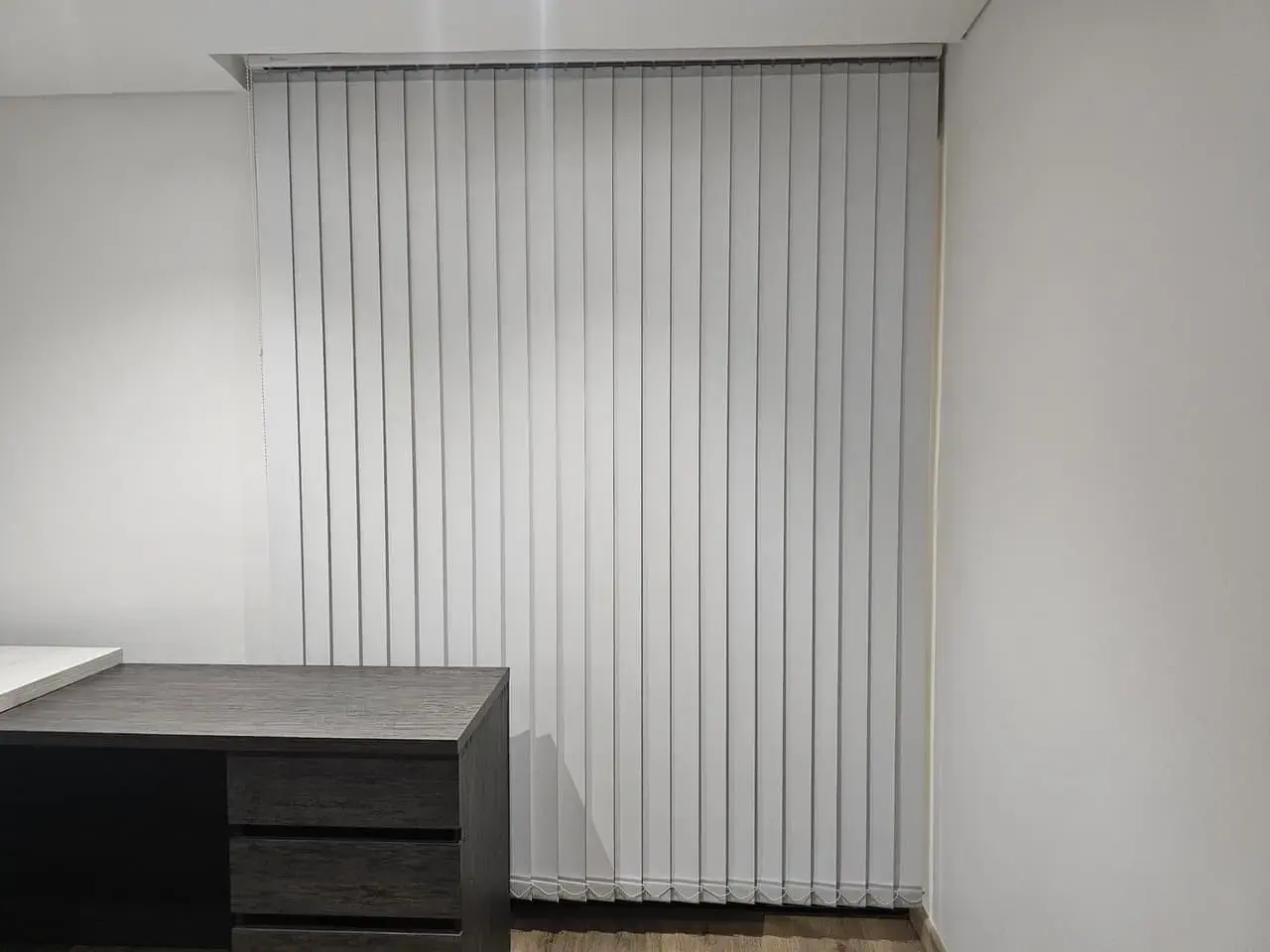 Escritorio con cajones junto a cortinas verticales
