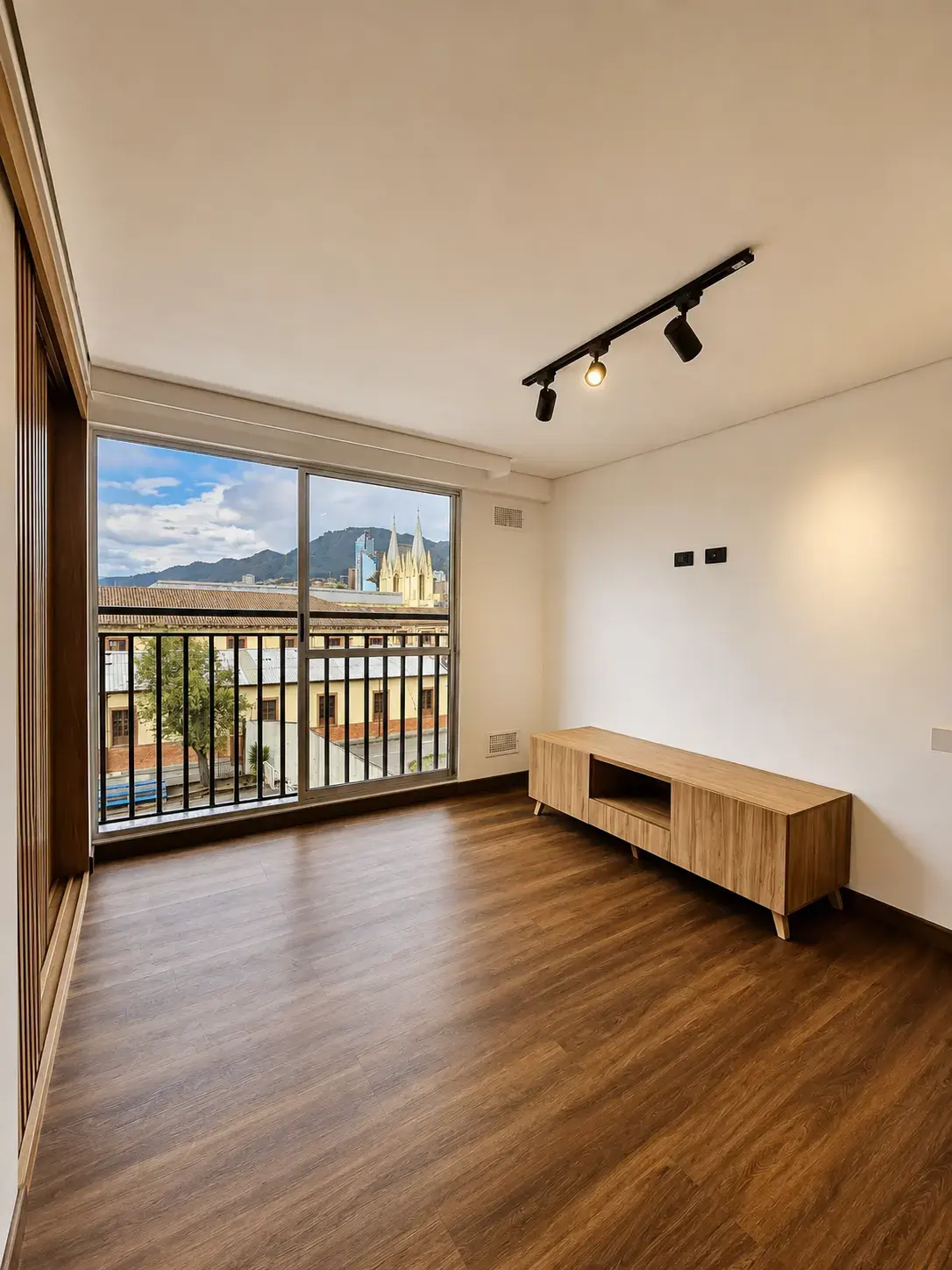 Sala vacía con ventanal, balcón y mueble de televisión de madera