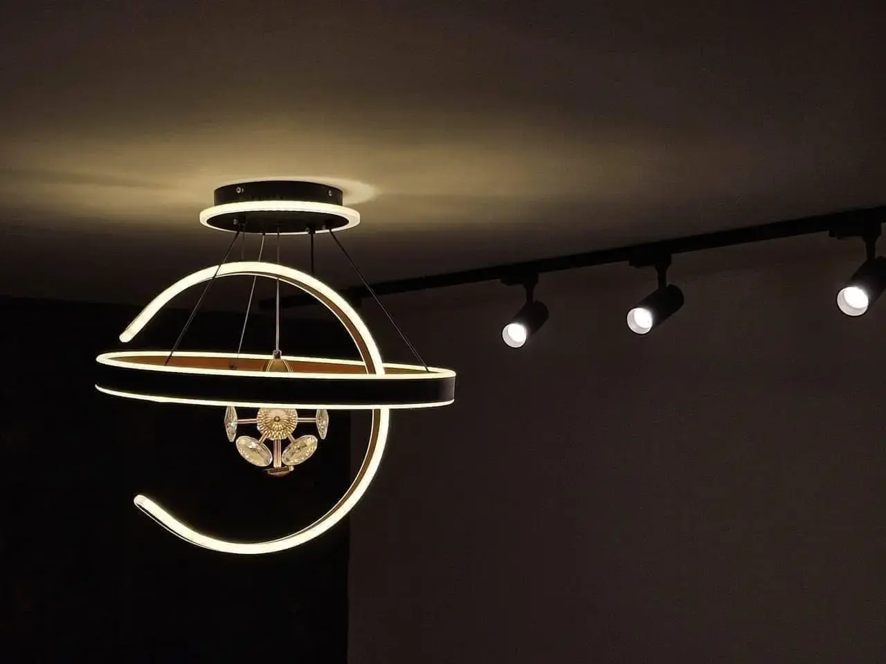 Lámpara de techo circular y riel de luces en una sala oscura